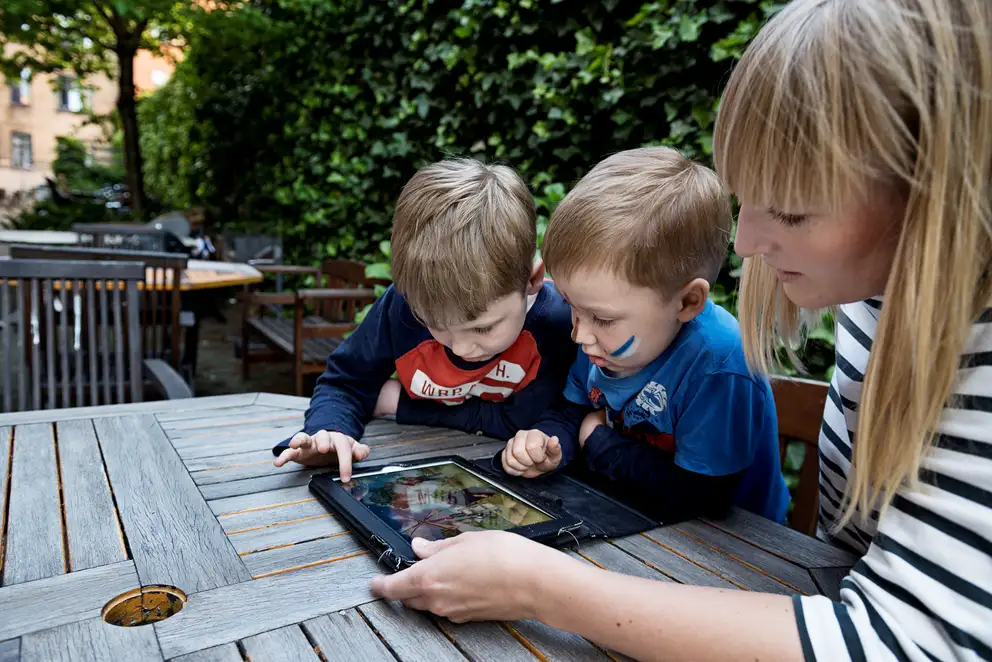 To børn og en voksen med en iPad.