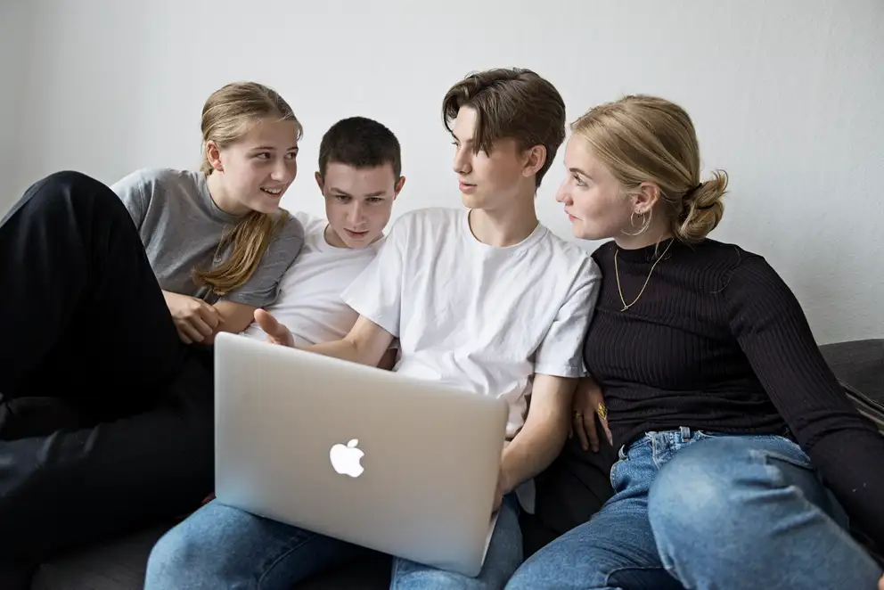 Fire unge mennesker sidder med en computer.