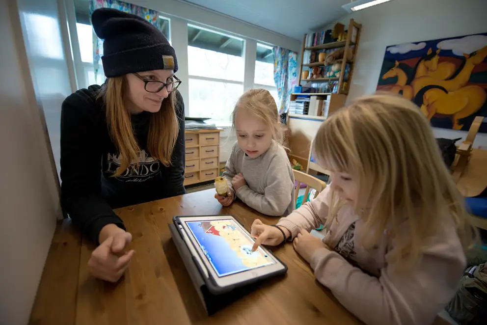 To børn og en voksen leger med en iPad.